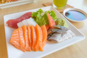 salmon and other fish raw with wasabi and sauce on table wood in