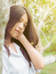 Portrait image of beautiful teenager girl loneliness in trees garden. Fashion sexy woman in white...