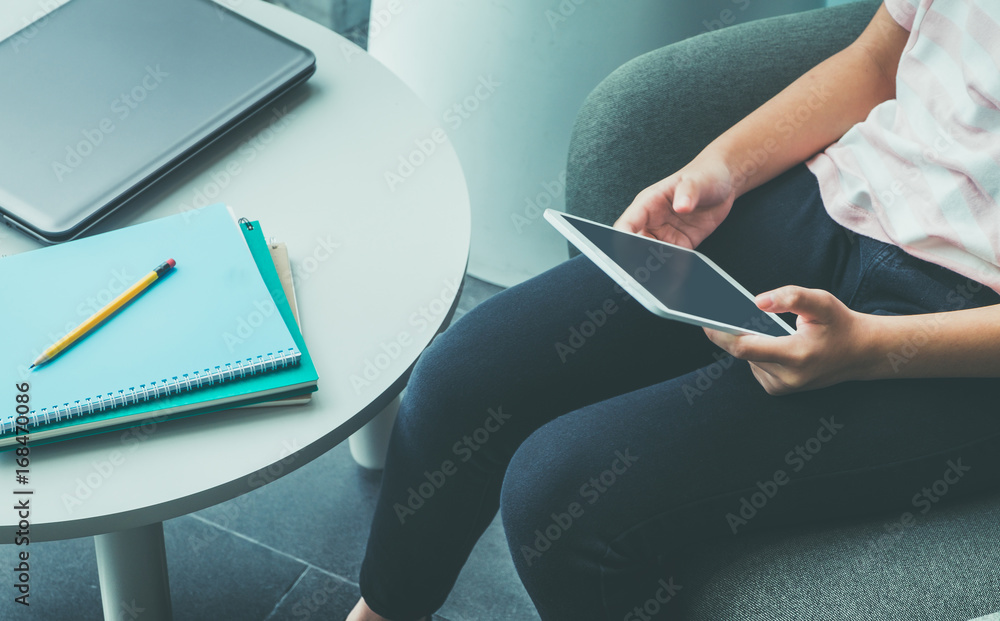 Poster Close up hand of girl sitting and touch blank screen of tablet computer with notebook and pencil on table in campus,Online education (e-learning) concept,Blank screen for adding design,clipping path