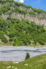 Fototapeta na wymiar A small blue river flows in the mountainous country of Georgia.