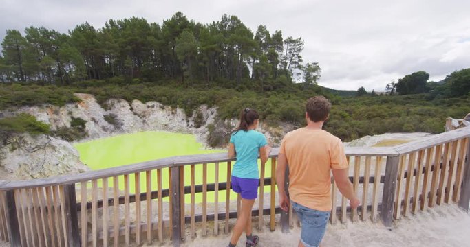 New Zealand travel tourist couple looking at colorful green pond. Tourists enjoying famous attraction on North Island, geothermal pools at Waiotapu, Rotorua, New Zealand.