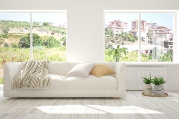 Fototapeta premium Idea of white room with sofa and summer landscape in window. Scandinavian interior design. 3D illustration