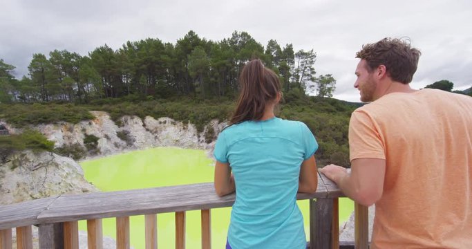 New Zealand travel tourists looking at colorful green pond. Tourist couple enjoying famous attraction on North Island, geothermal pools at Waiotapu, Rotorua, New Zealand.