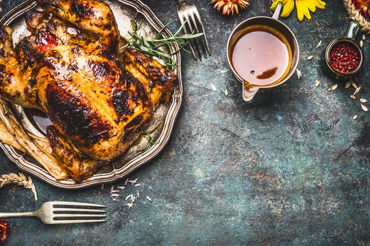 Roasted turkey with sauce served for Thanksgiving dinner on rustic table background, top view