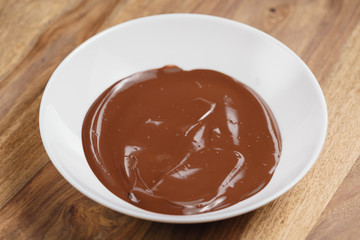 shot of melted premium dark chocolate in white bowl
