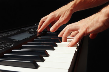 Hands of pianist playing the electronic organ on a black background
