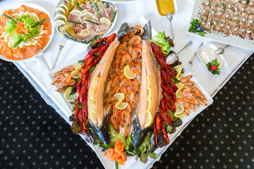 Shrimp, Crayfish, Salmon on a buffet table decorated with lemon, on a white plate