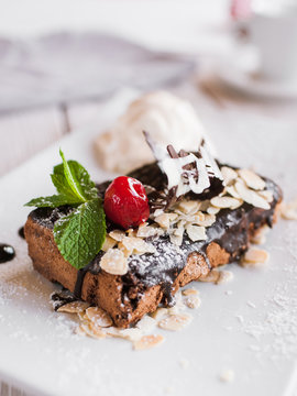 Chocolate pie serving in restaurant on white plate with decoration from cherry, almond and mint. Delicious dessert with ice-cream ball, close up picture
