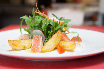 dish of potatoes and fish with fresh herbs and vegetables. closeup