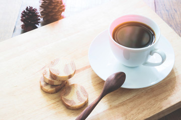 A cup of coffee with cookies on wood table, Autumn color tone with sunlight
