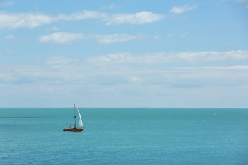 Fototapeta na wymiar Yacht sails by sea, travel, blue sky and beautiful clouds