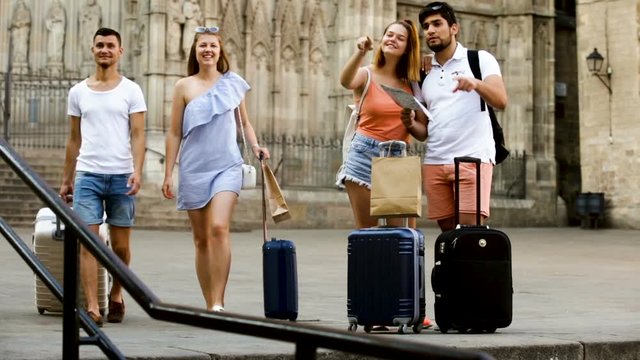 Positive man and woman traveling with map and baggage looking attraction
