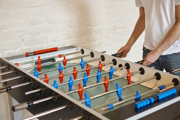 People, leisure, entertainment, fun and tabletop games concept. Unrecognizable male kicker enjoying...