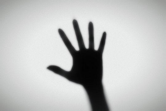 Shadow of a hand behind a frosted glass