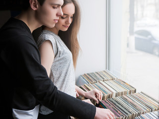 Happy young family choosing music together. Love couple with common interests, retro vinyl records