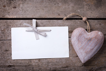 Empty tag with bow and decorative heart on rustic wooden background.