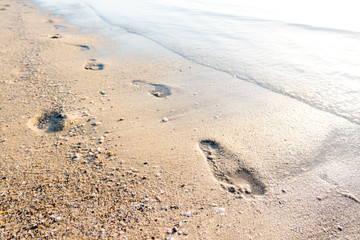 Footprints in sand at tropical beach in sunset.
