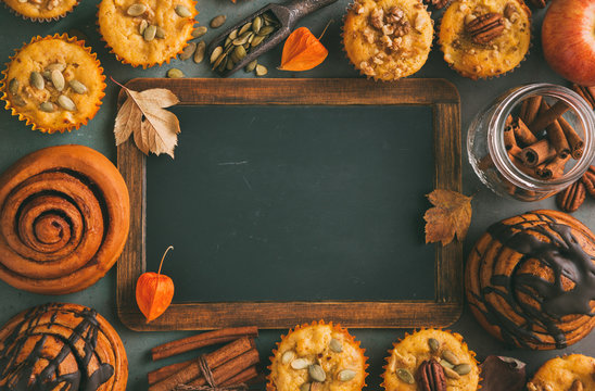 Freshly baked pumpkin muffins and cinnamon rolls with empty chalkboard. Autumn menu
