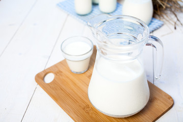 milk and glasses of milk on a wooden rustic table.