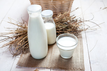 milk and glasses of milk on a wooden rustic table.