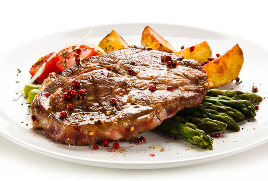 Grilled beef steaks,chips and asparagus on white background