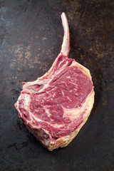 Raw dry aged Wagyu Tomahawk Steak as close-up on old board