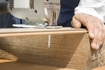 Stolarz przecina panel podłogowy wyrzynarką.