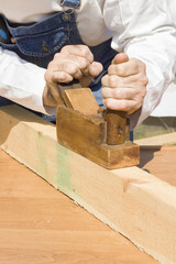 Robotnik budowlany hebluje kantówkę za pomocą ręcznego hebla