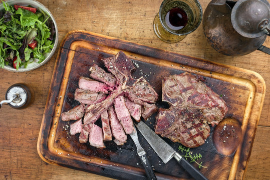 Two Barbecue dry aged Wagyu Porterhouse Steaks with Rocket Salad as close-up on a cutting board