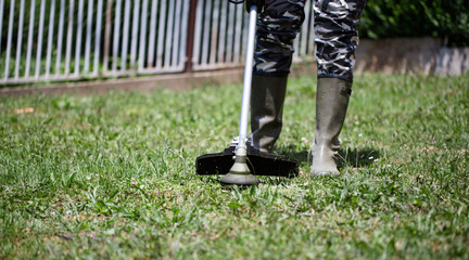 Man working with grass trimmer in home yard or garden