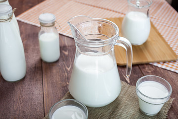 milk and glasses of milk on a wooden rustic table.