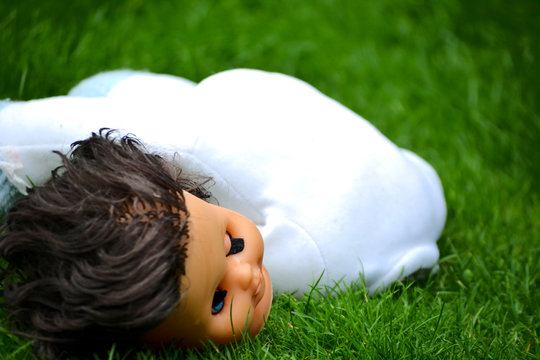 Doll head and body on the grass close up