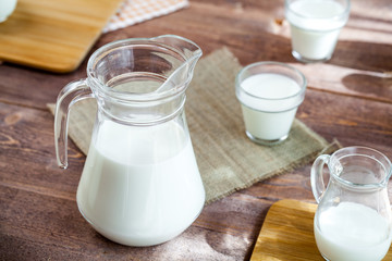 jug of milk and glasses of milk on a wooden rustic table.