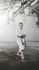 Caucasian female in Kimono practicing karate, Japanese martial arts. Old warehouse indoor shot