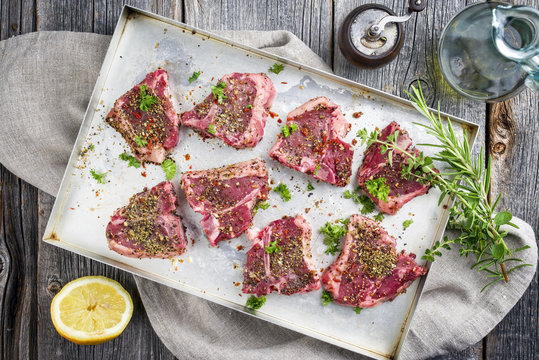 Raw T-Bone Lamb Steak with Seasonings as top view on a metal sheet