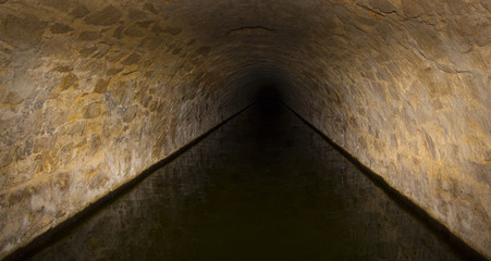 Flooded round sewer tunnel is reflecting in water