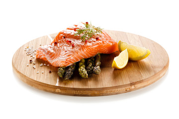 Fresh raw salmon with asparagus on cutting board on white background