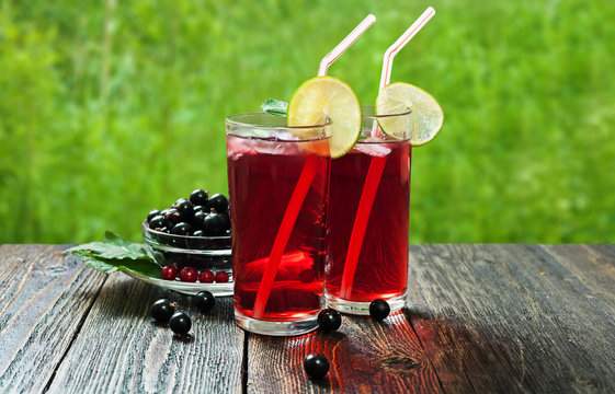 Blackcurrant juice with lime in tall glasses on a wooden table