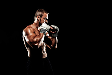 Sportsman muay thai boxer fighting in boxing cage. Isolated on black background. Box trainer on ring hitting