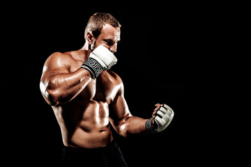 Sportsman muay thai boxer fighting in boxing cage. Isolated on black background. Box trainer on ring hitting