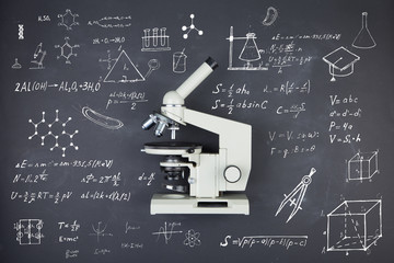 Science concept microscope on the table in the auditorium, blackboard background
