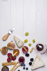 Different types of cheeses with wine glass and fruits