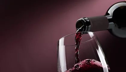 Fototapeten Rotwein in ein Weinglas gießen © stokkete