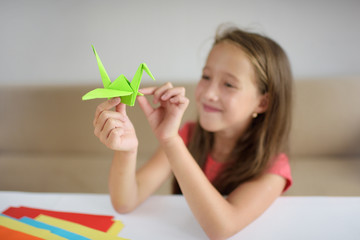 The girl puts origami from paper. lesson of origami