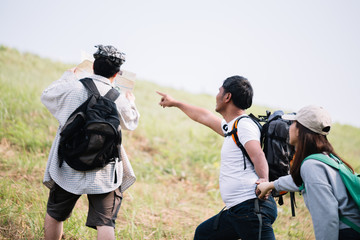 Group of backpacking hikers going to mountain top and navigating by map. Backpackers or Hikers travel concept. Selective focus.