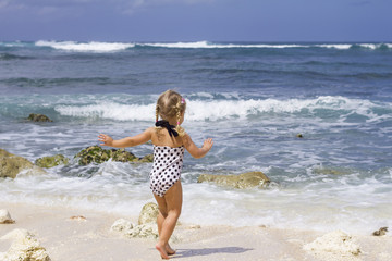 Fototapeta na wymiar Child on the ocean background / Little girl is running to the ocean