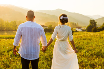 Couple walking on the field with sunset view