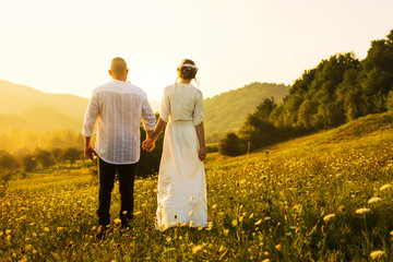 Fototapeta premium Couple walking on the field with sunset view
