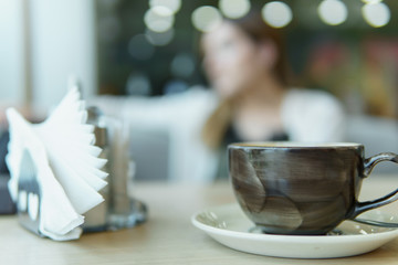 Blurred woman in cafe. Selective focus on cup of coffee