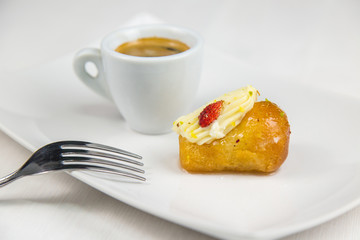 Neapolitan babà and coffee on white white dish